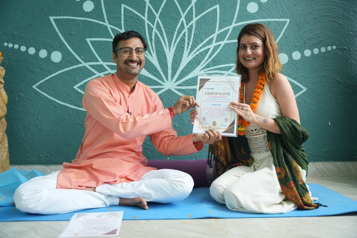 Teacher presenting a Yoga Alliance certificate to a graduating student at Sri Yoga Ashram