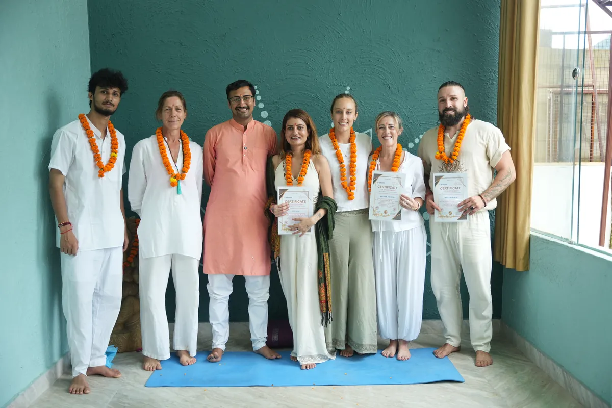 Graduating group in white holding their certificates with their teacher at Sri Yoga Ashram