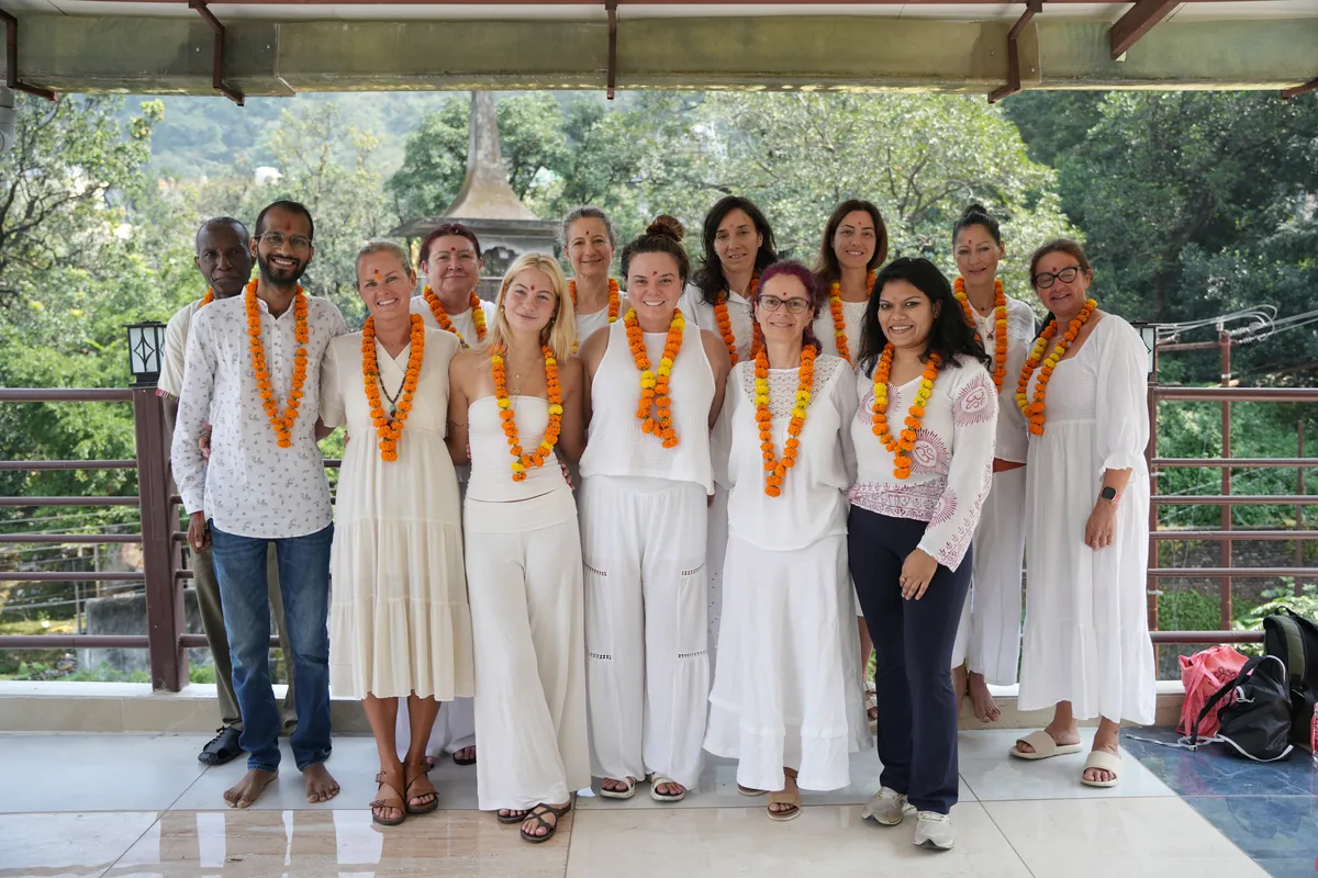 Group of students and teachers wearing marigold garlands outside Sri Yoga Ashram in Rishikesh