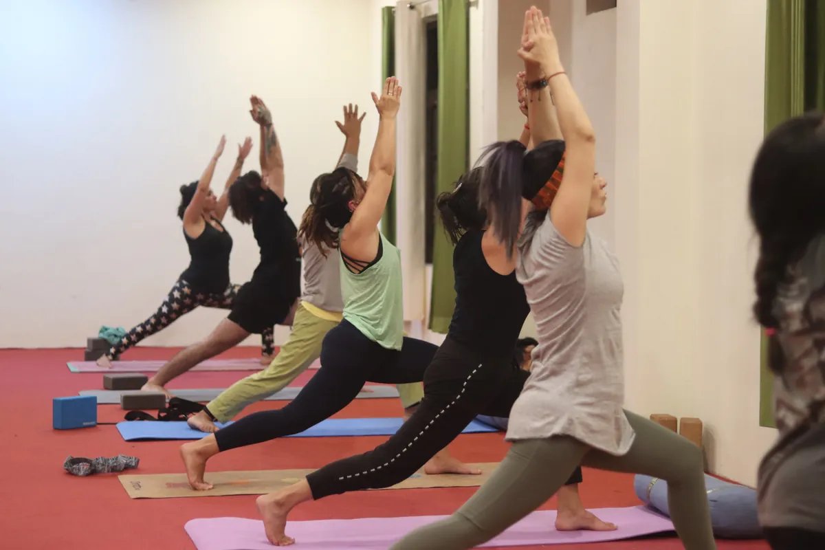 Kundalini yoga students in a standing sequence in the yoga hall at Sri Yoga Ashram