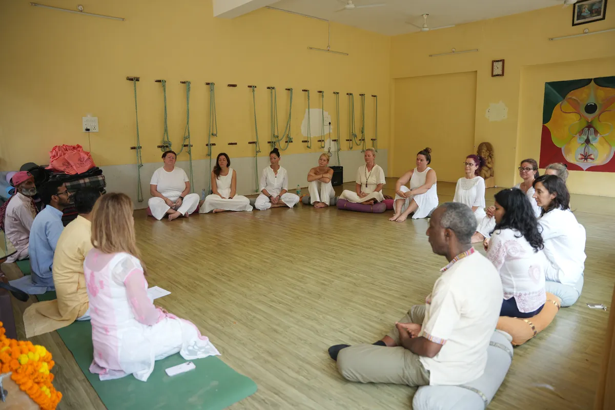 Teacher leading a meditation class seated in a circle with students in Rishikesh