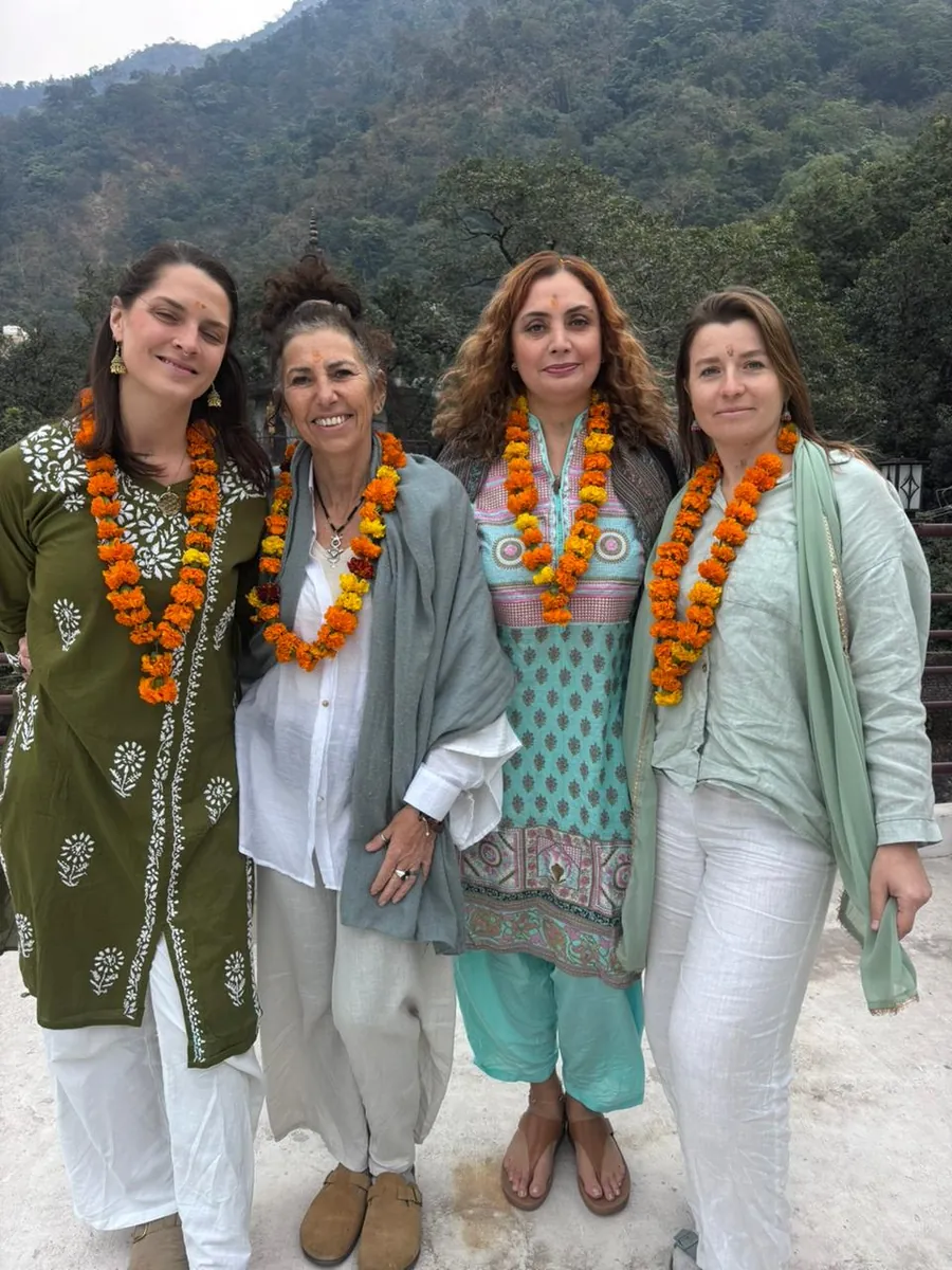 Retreat guests wearing marigold garlands beside the river in Rishikesh