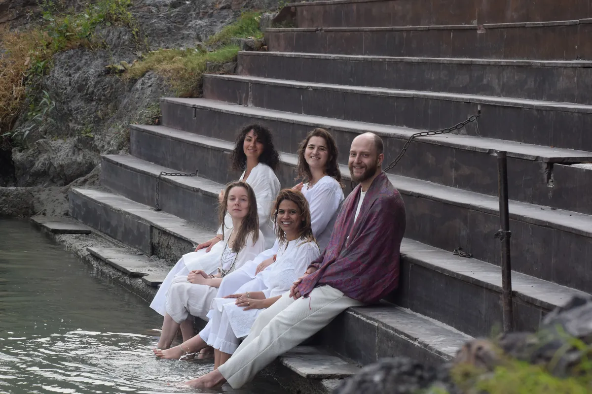 Retreat guests sitting on the ghat steps at the edge of the Ganges in Rishikesh
