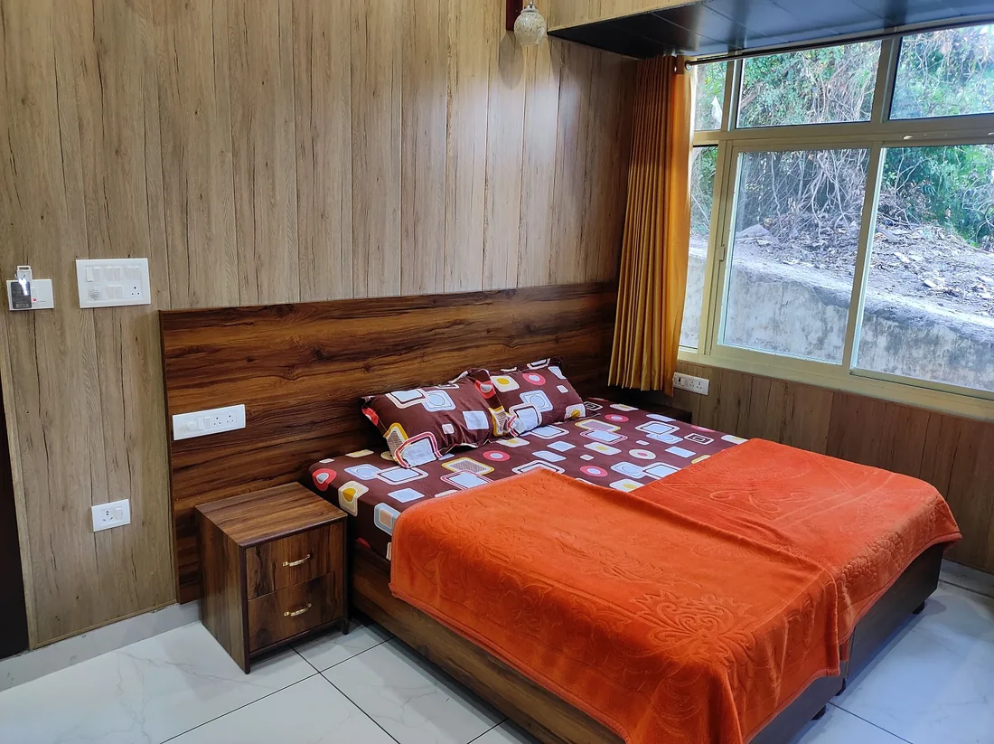 Bright wood panelled guest room at Sri Yoga Ashram Rishikesh with double bed and large window