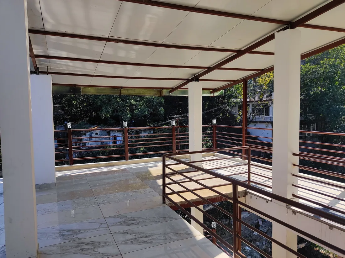 Covered rooftop terrace overlooking trees at Sri Yoga Ashram in Rishikesh