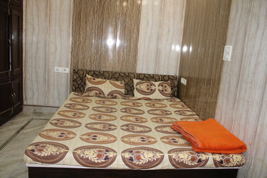Double bed with patterned cover in a guest room at Sri Yoga Ashram Rishikesh