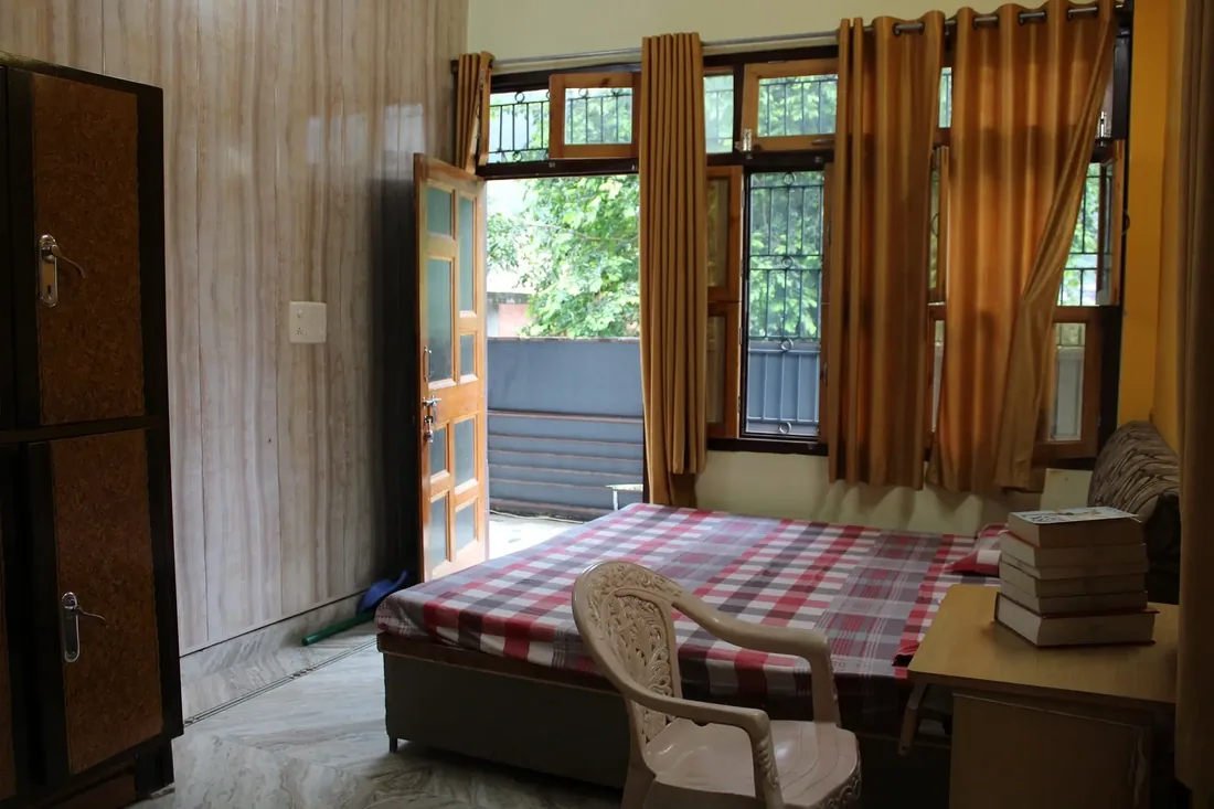 Guest room with double bed, desk and wardrobe at Sri Yoga Ashram Rishikesh
