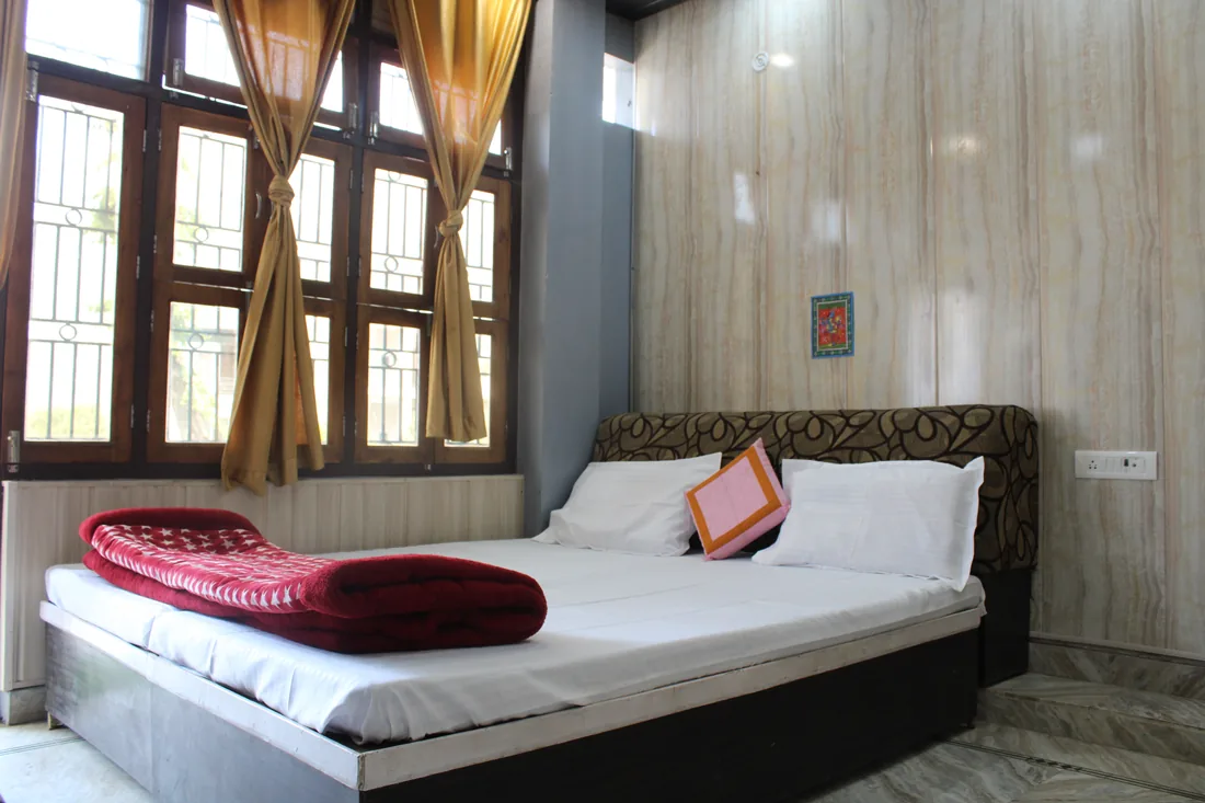Guest room double bed with white bedding and curtained window, Sri Yoga Ashram Rishikesh