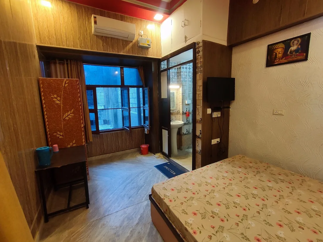 Guest room at Sri Yoga Ashram Rishikesh with double bed, air conditioner and ensuite bathroom