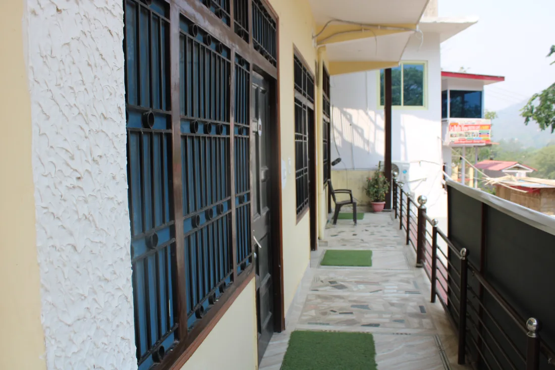 Open corridor outside guest rooms at Sri Yoga Ashram in Rishikesh with hill views