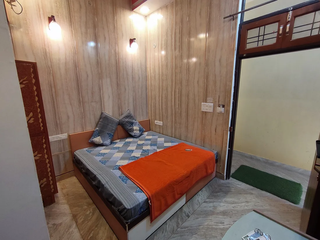 Wood panelled guest room at Sri Yoga Ashram Rishikesh with double bed and open doorway