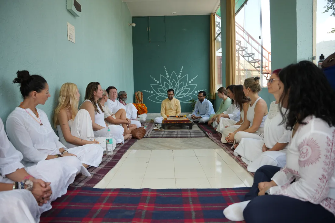 Students sitting in circle for opening ceremony with teacher at Rishikesh yoga ashram hall