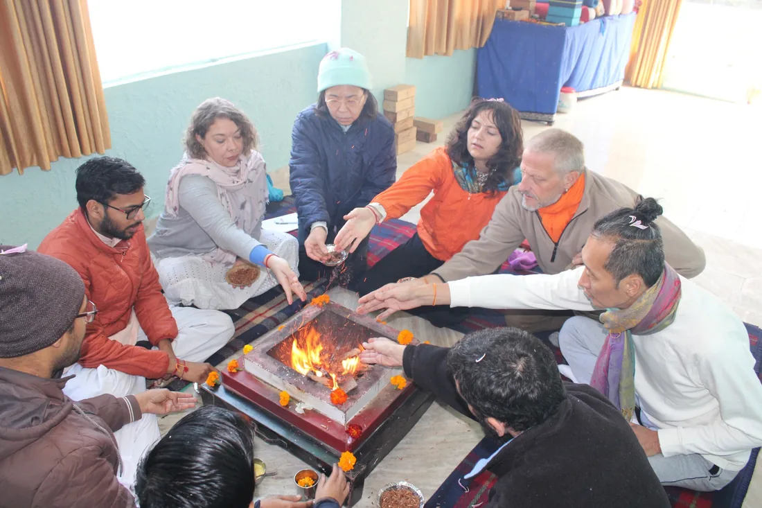 Students and priest offering grains into the sacred fire at a Rishikesh havan ceremony