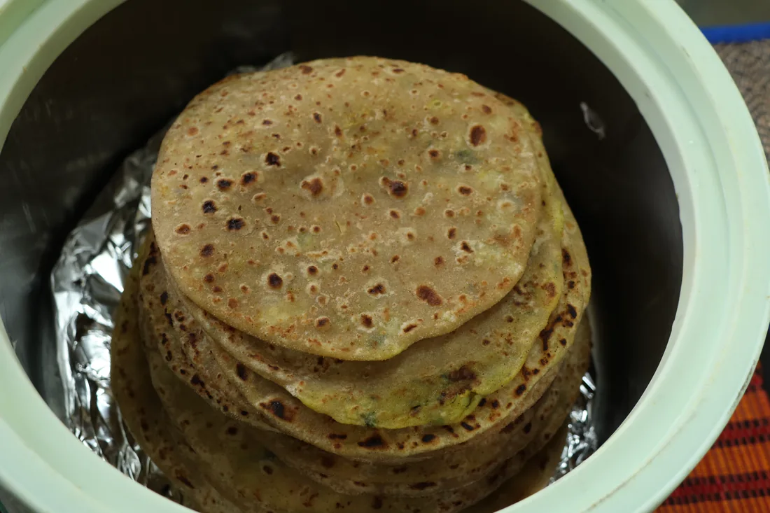 Stack of warm stuffed Indian flatbreads in a serving pot at Sri Yoga Ashram