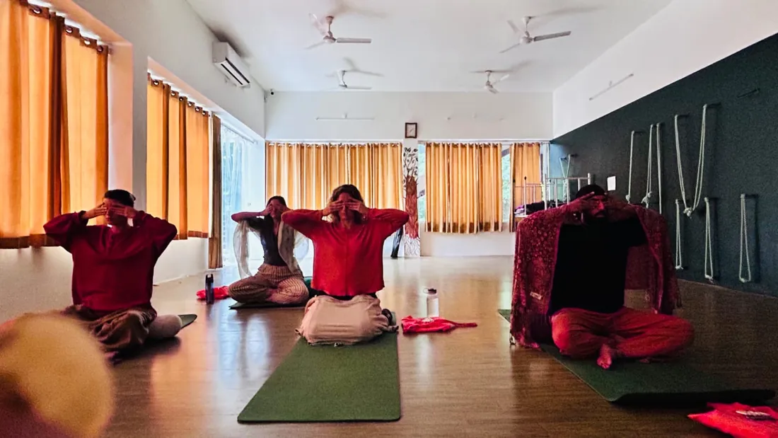 Students practising Shanmukhi mudra during a pranayama class in the yoga hall at Sri Yoga Ashram