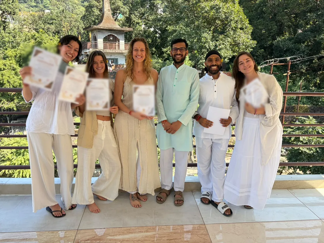 Graduates of the October 2026 200 hour batch holding their certificates with their teachers on the ashram terrace