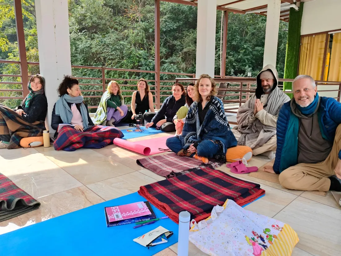 Students sit with blankets during a class on the forest terrace at Sri Yoga Ashram