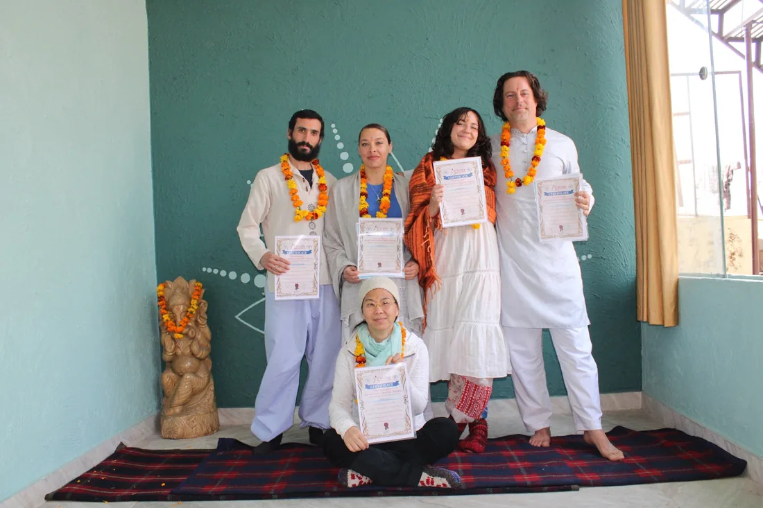 Yoga teacher training graduates with marigold garlands holding certificates at Sri Yoga Ashram Rishikesh