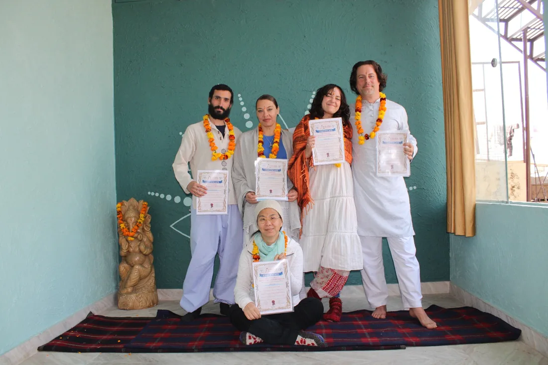 Yoga teacher training graduates with marigold garlands and certificates at Sri Yoga Ashram Rishikesh