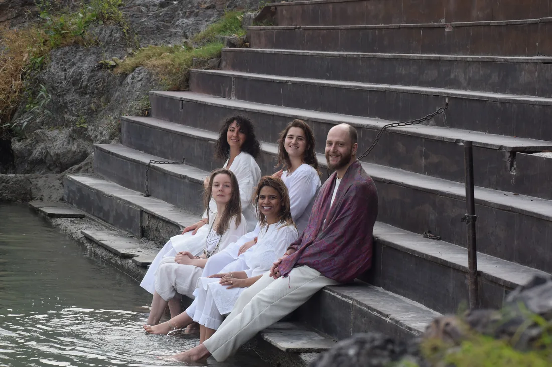 Yoga students in white sit on river ghat steps in Rishikesh India