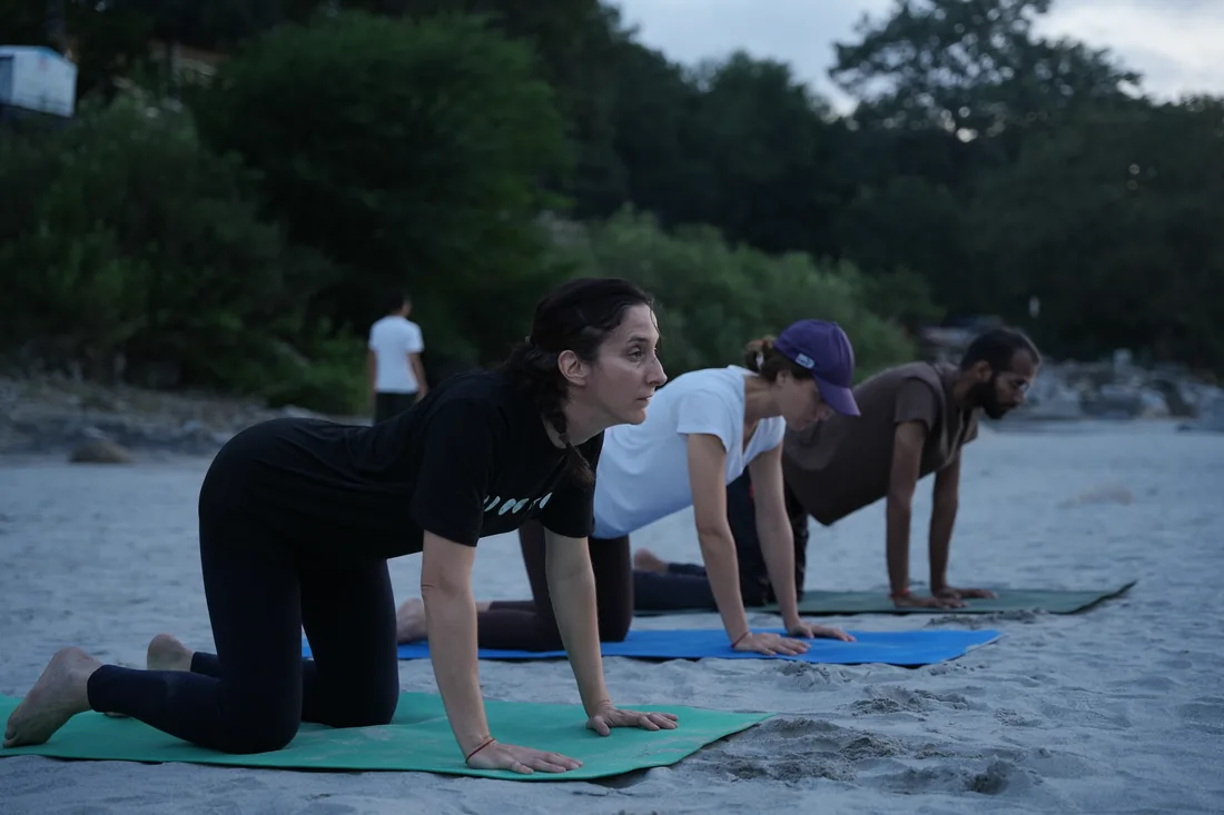 Students in tabletop pose on mats beside the Ganga at Sri Yoga Ashram, Rishikesh