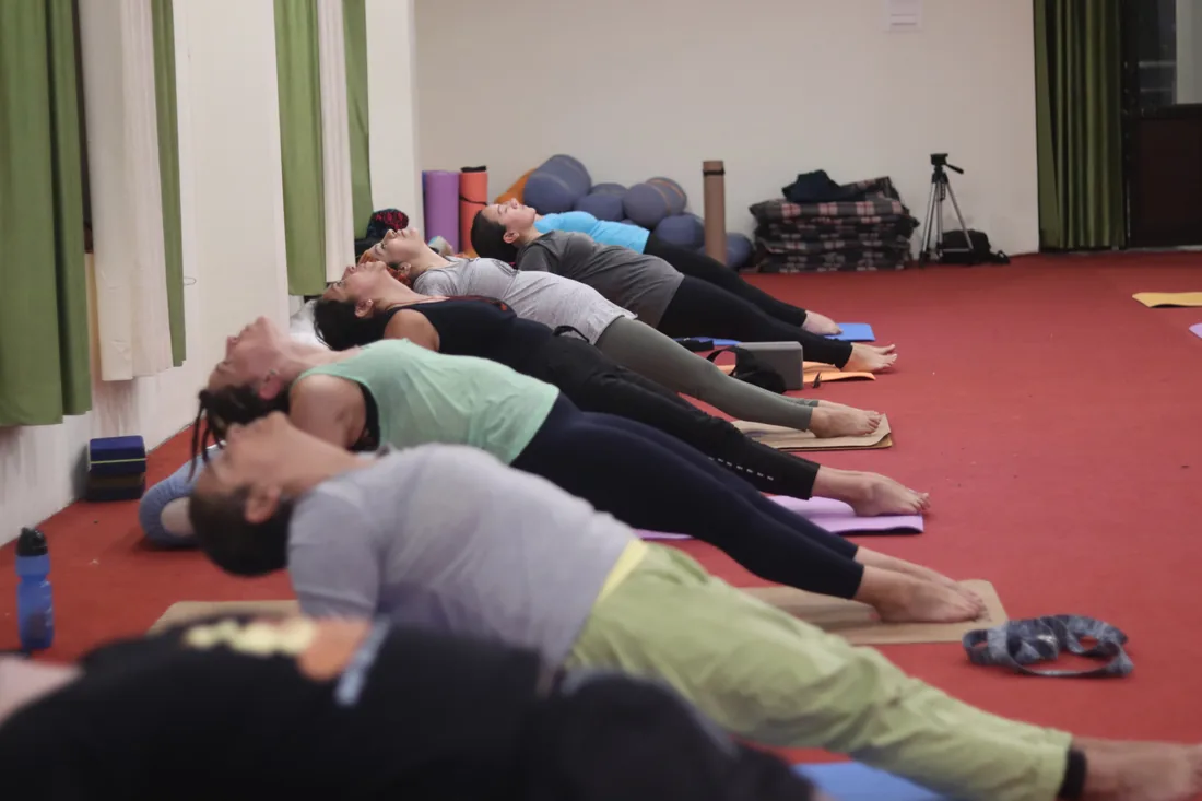 Yoga students resting in fish pose during a class at Sri Yoga Ashram Rishikesh