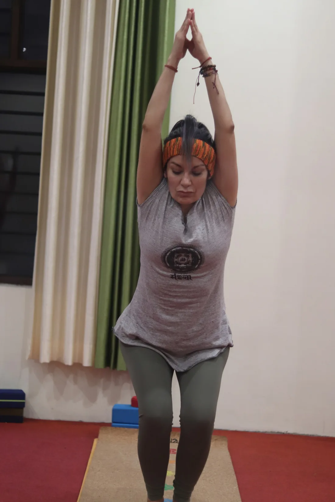 Woman in upward salute with joined palms during a yoga class at Sri Yoga Ashram